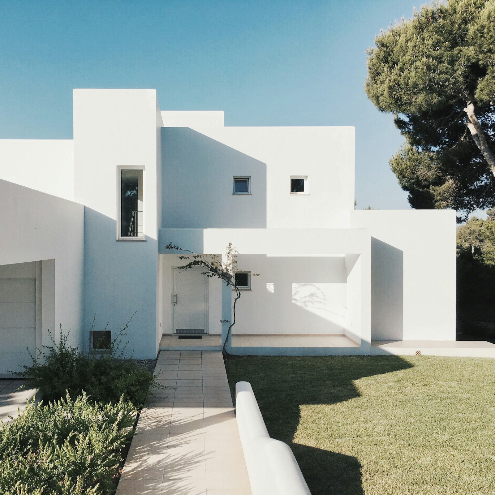 White stucco house with a stone walkway and trimmed lawn