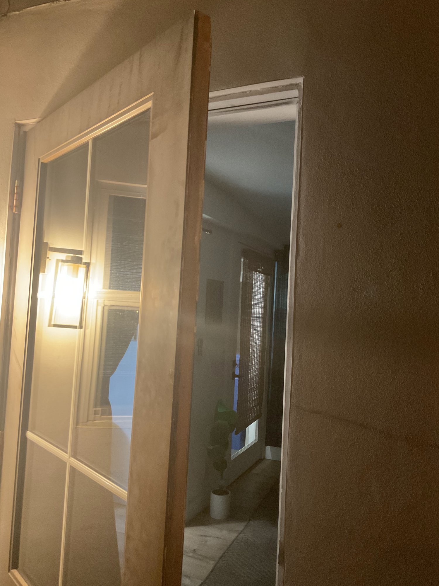 Wall sconce lighting a hallway through a glass door