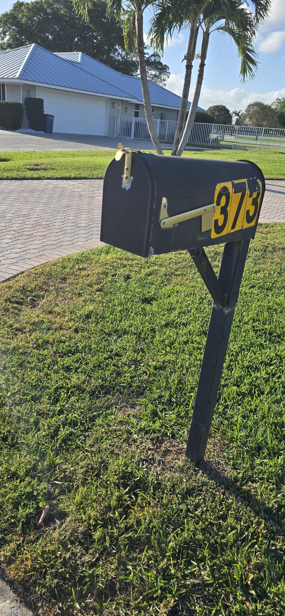 Black mailbox with yellow house numbers on a front lawn